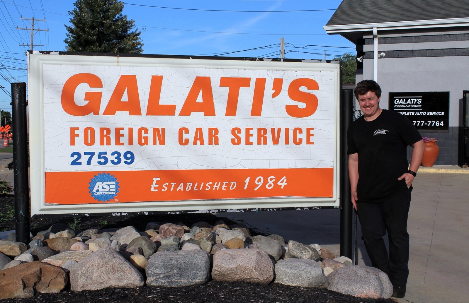 Austin Detwiler beside the original Galati's Foreign Car Service ‘Established 1984’ sign on Lorain Road